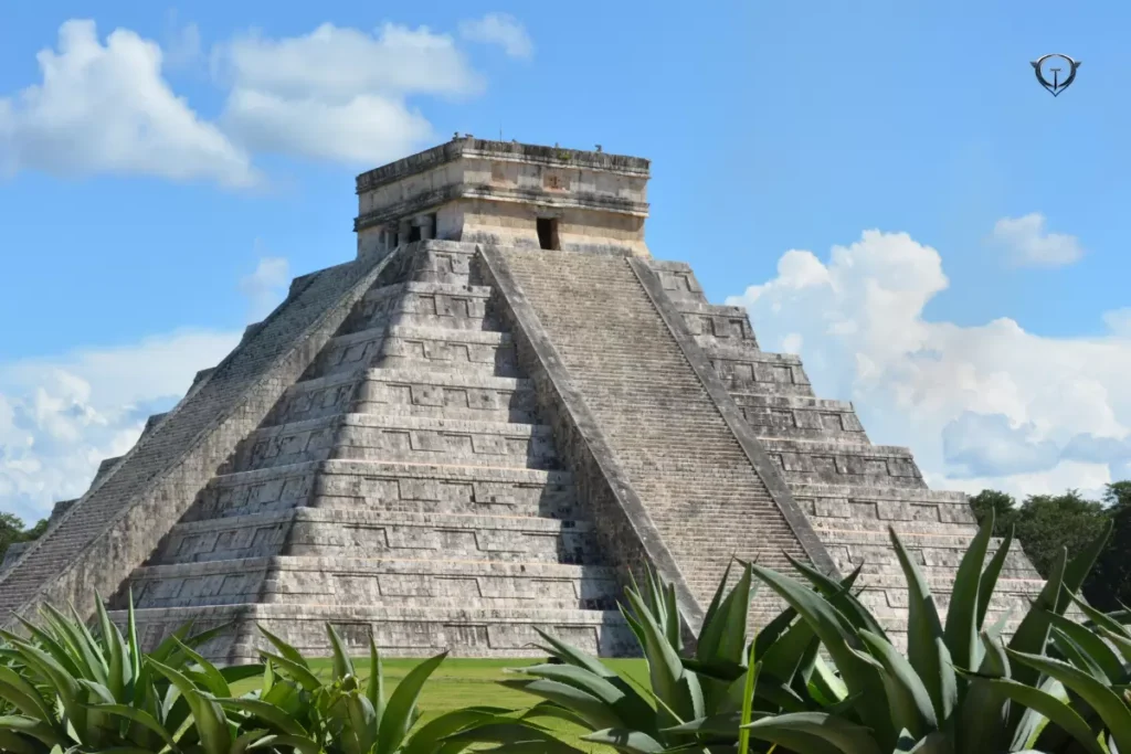 Chichen Itza with the large pyramid and ancient ruins surrounded by trees.